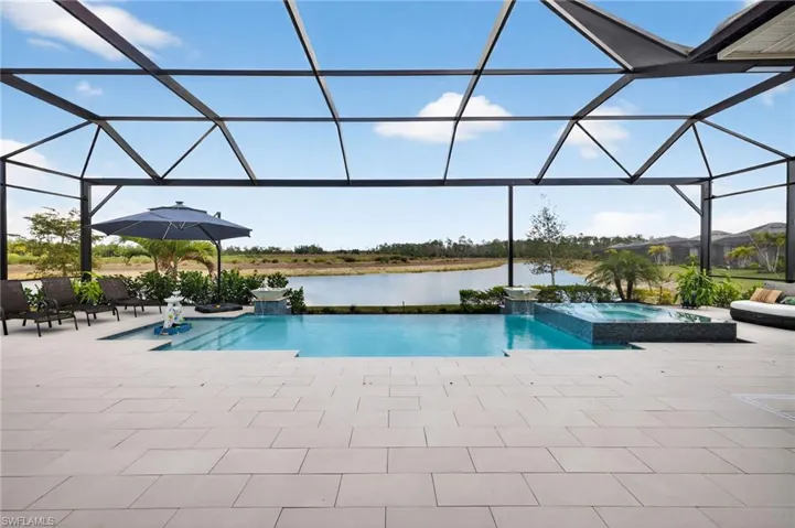 Combined pool / hot tub featuring a sunroom, a lanai, a water view, and a patio