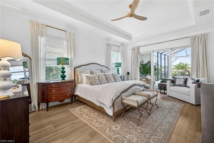 Bedroom featuring access to outside, light wood finished floors, ceiling fan, ornamental molding, and a tray ceiling