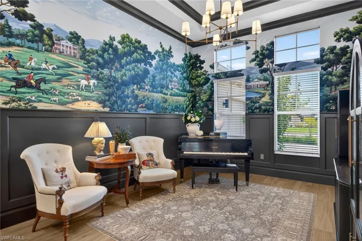Sitting room featuring wood finished floors, suspended lighting, a decorative wall, and a high ceiling