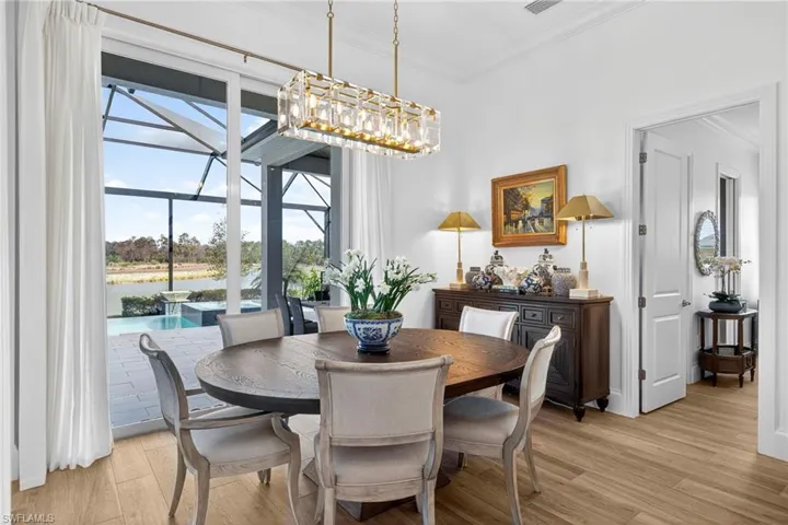 Dining area with light wood-style floors, ornamental molding, and a sunroom
