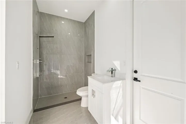 Full bathroom featuring vanity, a walk in shower, recessed lighting, and light tile patterned floors