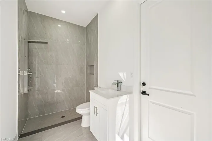 Bathroom featuring a walk in shower, vanity, recessed lighting, and light tile patterned floors