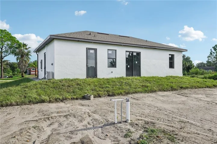 Back of property featuring stucco siding and roof with shingles