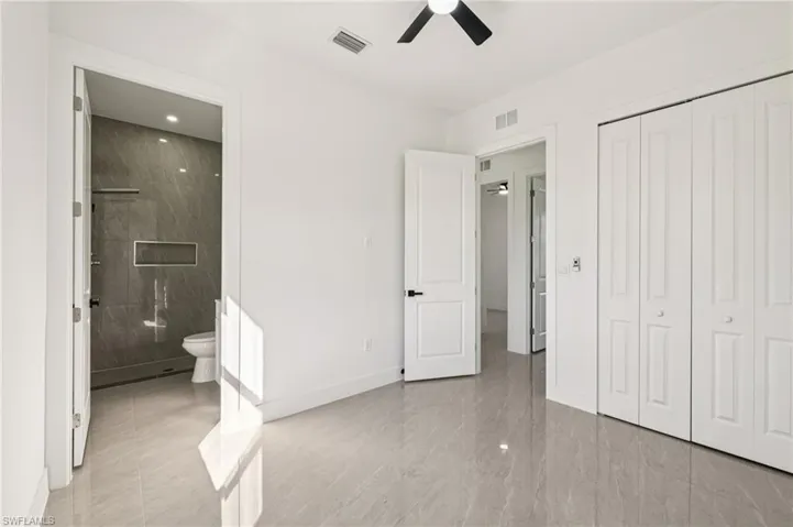 Unfurnished bedroom with a ceiling fan, ensuite bathroom, and a closet