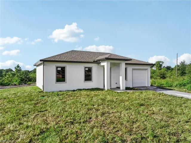 Prairie-style home featuring stucco siding, driveway, a front yard, and an attached garage