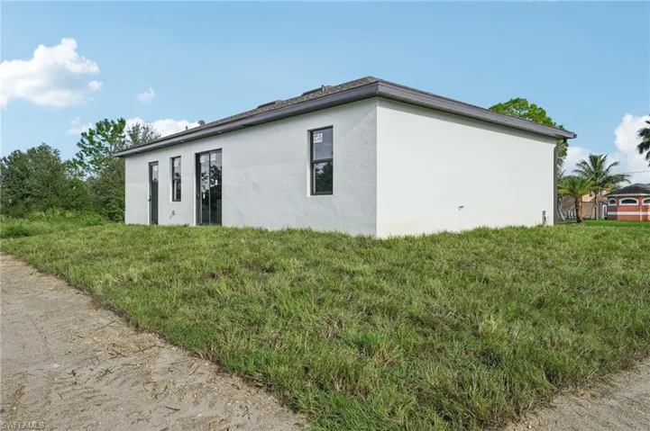 View of side of property with stucco siding and a yard