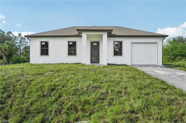 Prairie-style house featuring stucco siding, an attached garage, concrete driveway, a front yard, and a shingled roof