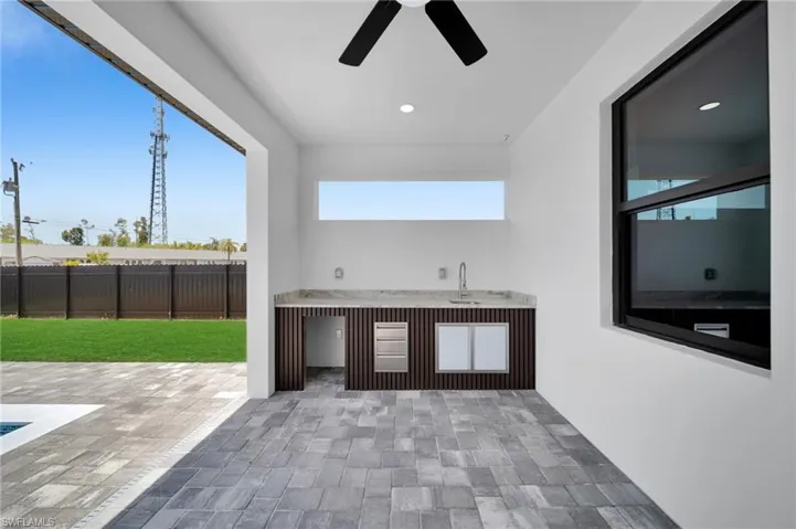 View of patio / terrace with fence, a ceiling fan, and a bar