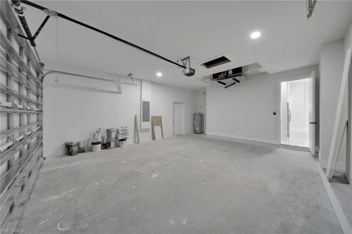 Garage featuring a garage door opener, water heater, recessed lighting, and electric panel