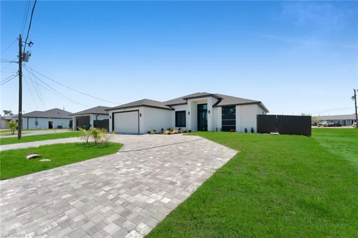 View of front of home featuring decorative driveway, a front yard, and a garage