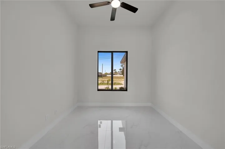 Empty room with light marble finish floors, ceiling fan, and baseboards