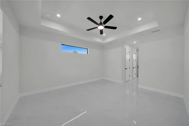 Unfurnished room with marble look tiles, recessed lighting, a raised ceiling, and baseboards