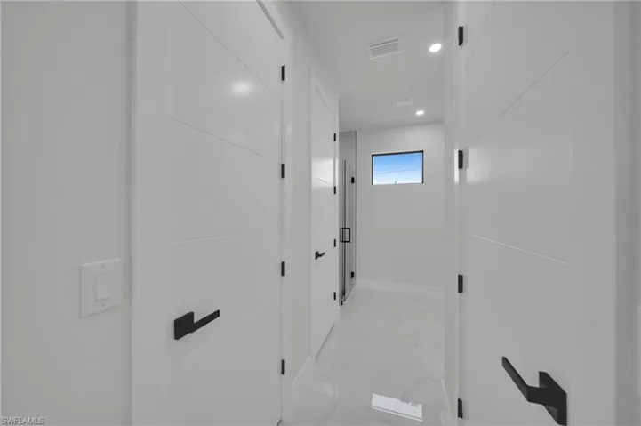 Hall with light marble finish floors, baseboards, and recessed lighting