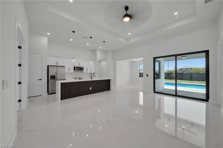 Kitchen featuring stainless steel appliances, a towering ceiling, a raised ceiling, ceiling fan, and a sink