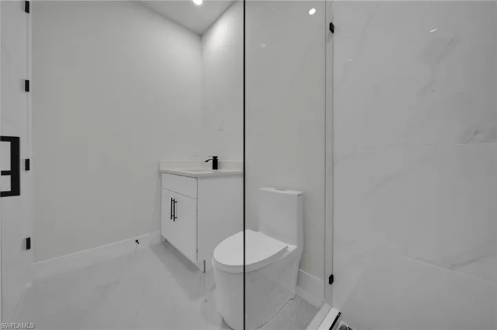 Bathroom featuring marble look tile flooring, toilet, vanity, and baseboards