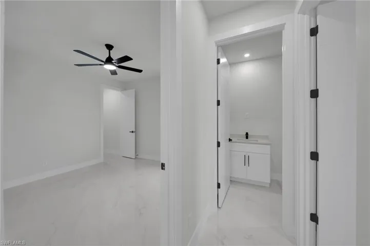 Corridor with light marble finish flooring, a sink, baseboards, and recessed lighting