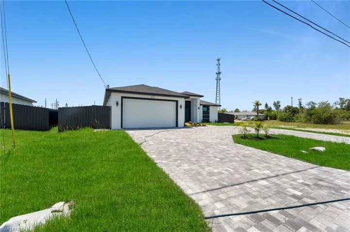 View of front facade featuring a garage, decorative driveway, and stucco siding