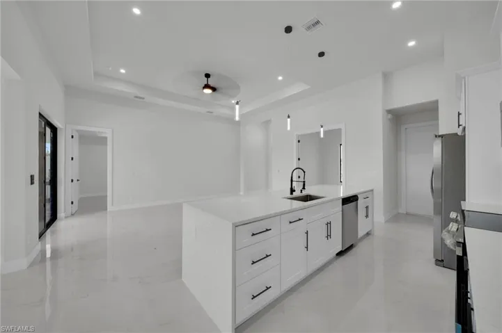Kitchen with a sink, appliances with stainless steel finishes, light marble finish flooring, a ceiling fan, and recessed lighting