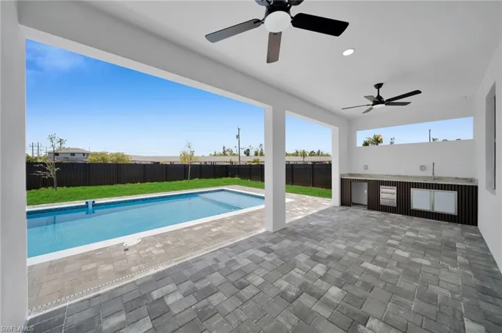 View of swimming pool featuring ceiling fan, a patio area, and a sink