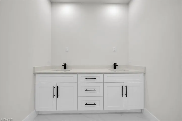 Bathroom with marble look tiles, baseboards, and double vanity