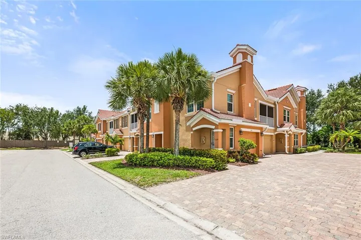 Townhome / multi-family property featuring a garage, a tiled roof, stucco siding, driveway, and a chimney