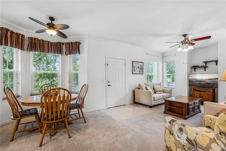 Dining area with a ceiling fan, light colored carpet, crown molding, and light tile patterned flooring