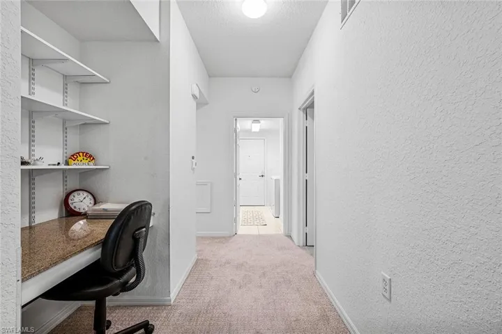 Carpeted office featuring a textured wall and a textured ceiling