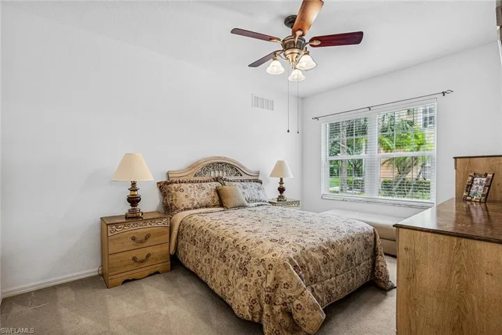 Bedroom with light colored carpet and a ceiling fan
