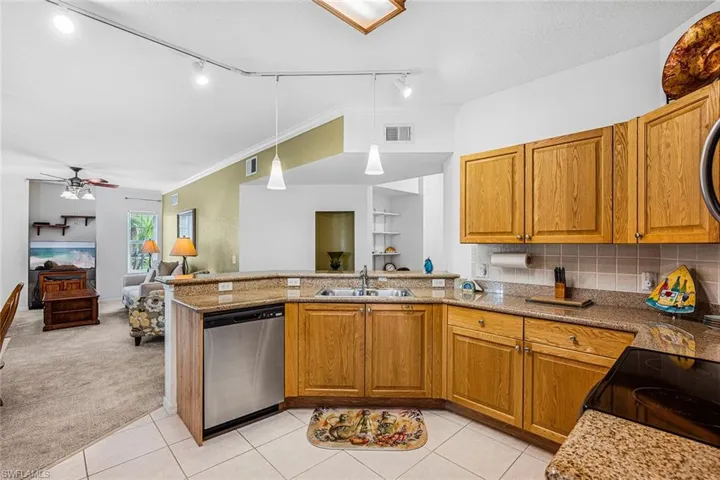 Kitchen with dishwasher, rail lighting, light colored carpet, a peninsula, and crown molding
