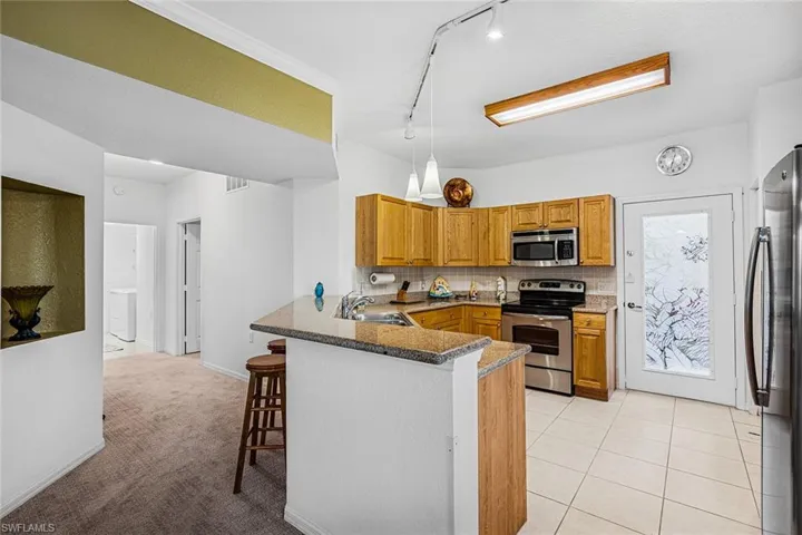 Kitchen featuring stainless steel appliances, a kitchen bar, a peninsula, and brown cabinets