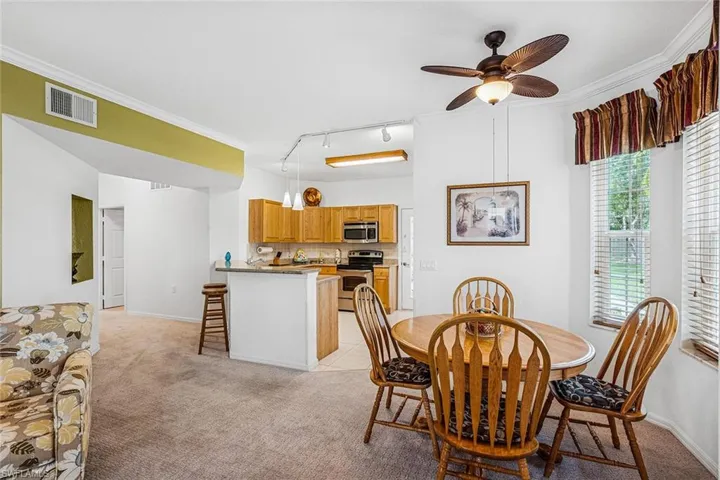 Dining room with light carpet, rail lighting, crown molding, and ceiling fan