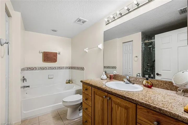 Full bathroom with tile patterned floors, a garden tub, vanity, a stall shower, and a textured ceiling