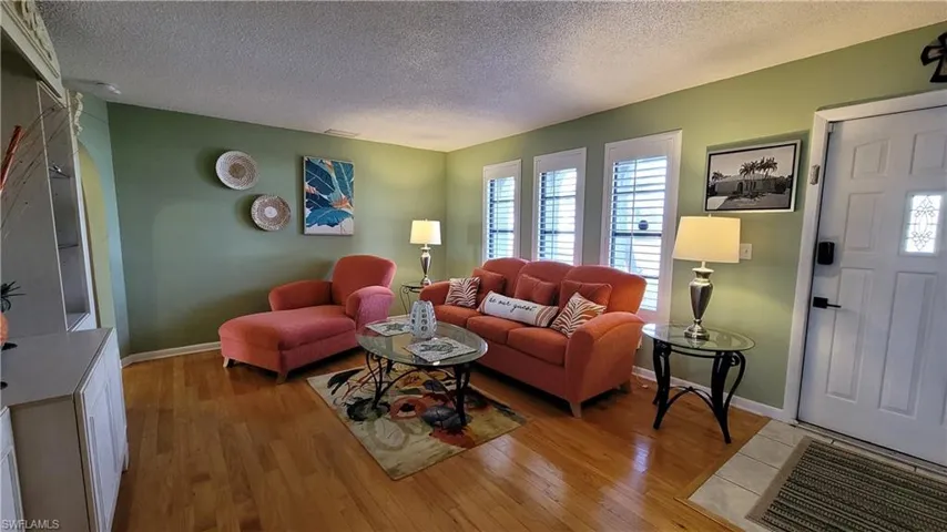 Living area with light wood-type flooring, a textured ceiling, and baseboards