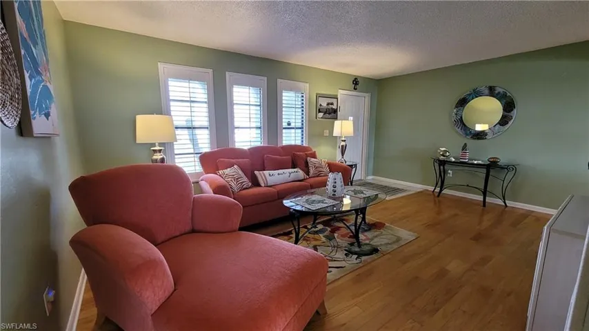 Living room featuring a textured ceiling, wood finished floors, and baseboards