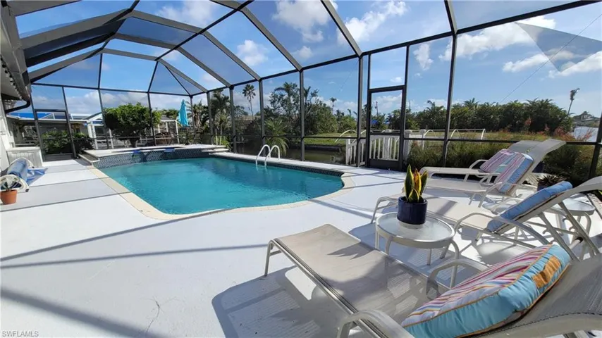 View of swimming pool featuring enclosure, a pool with connected hot tub, and a patio