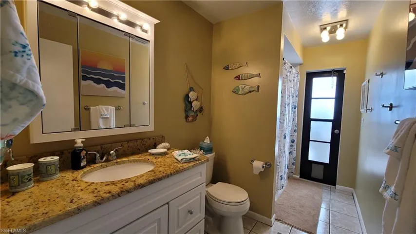 Full bathroom featuring toilet, vanity, a shower with curtain, baseboards, and tile patterned floors