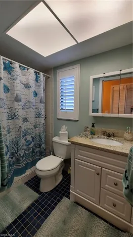 Full bathroom with vanity, tile patterned flooring, toilet, and a shower with curtain