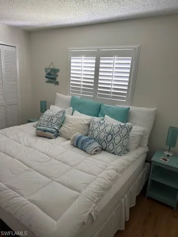 Bedroom with a textured ceiling, a closet, and wood finished floors