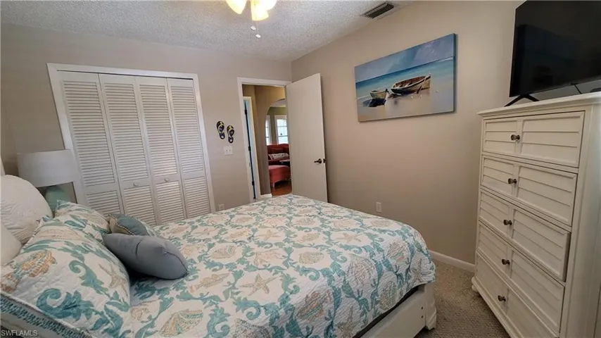 Bedroom featuring visible vents, arched walkways, a textured ceiling, carpet floors, and a closet