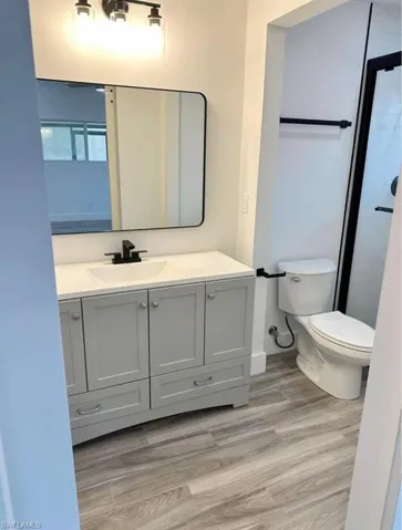 Full bath featuring vanity, light wood-style flooring, and a shower
