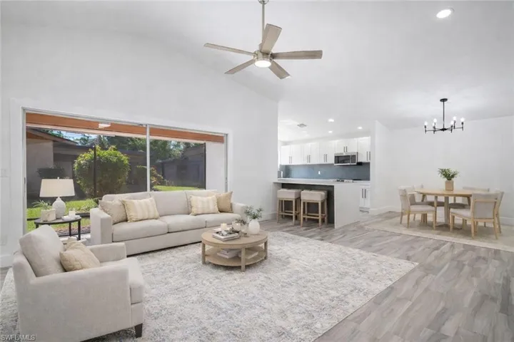 Living area with a ceiling fan, light wood finished floors, vaulted ceiling, and hanging lights