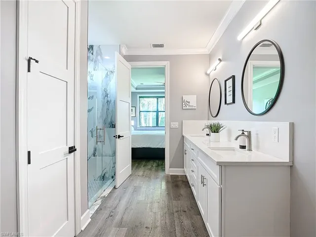 Bathroom with vanity, an enclosed shower, ornamental molding, and wood-type flooring