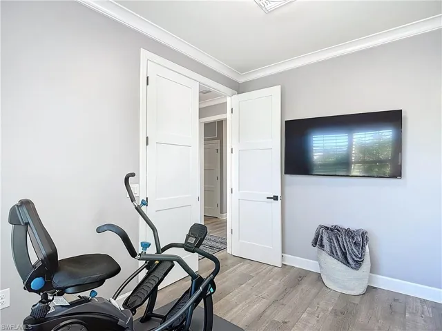 Bedroom #3 used as Exercise room featuring crown molding and light hardwood / wood-style floors