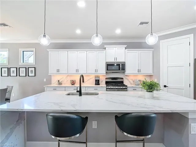 Kitchen with white cabinetry, appliances with graphite finishes, and decorative light fixtures