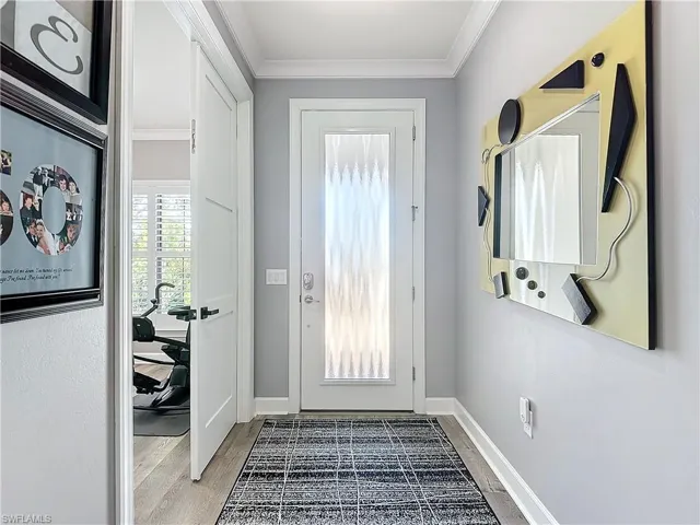Entryway with hardwood / wood-style floors and crown molding