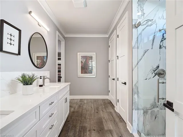 Bathroom featuring vanity, crown molding, hardwood / wood-style flooring, and walk in shower