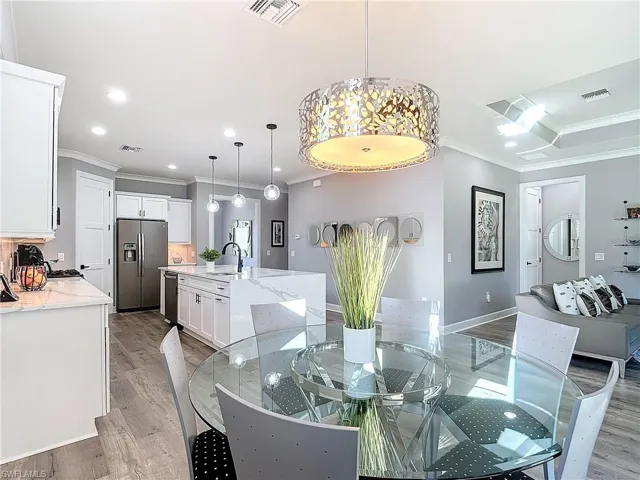 Dining space with crown molding, sink, and light wood-type flooring