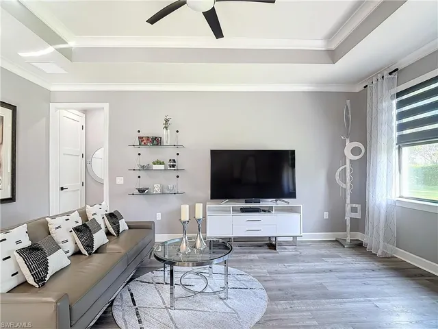 Living room featuring crown molding, hardwood / wood-style flooring, a tray ceiling, and ceiling fan