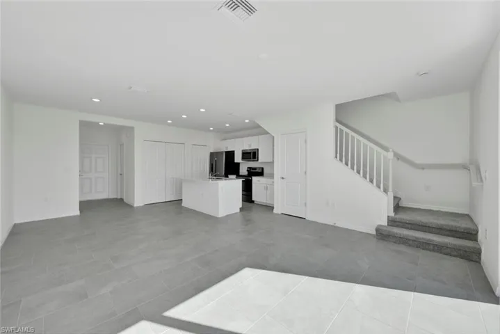 Unfurnished living room with stairway, recessed lighting, baseboards, and light tile patterned floors