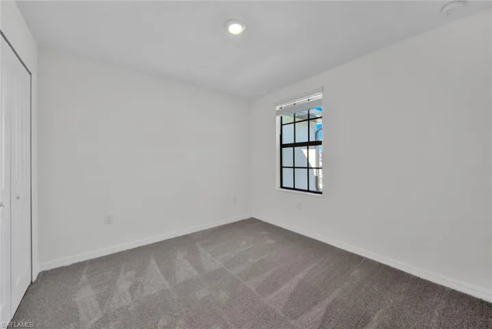 Unfurnished bedroom featuring dark colored carpet, baseboards, and a closet